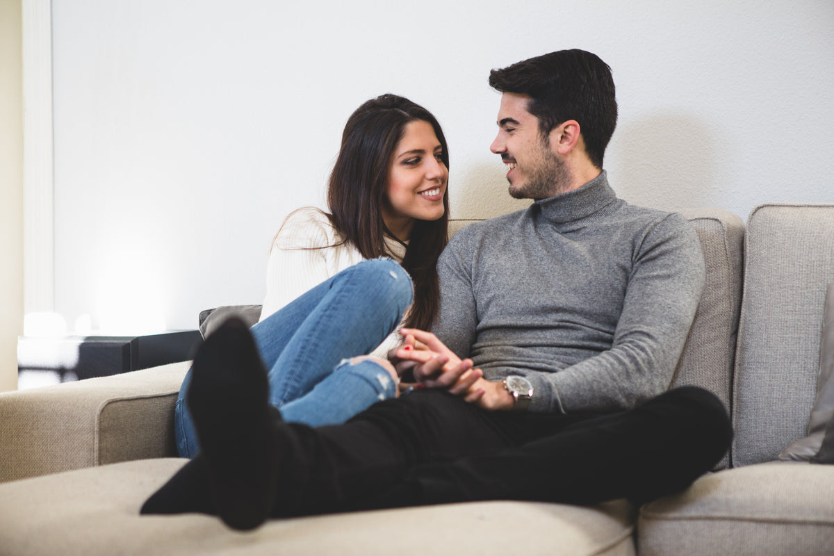 Couple sitting gray couch talking