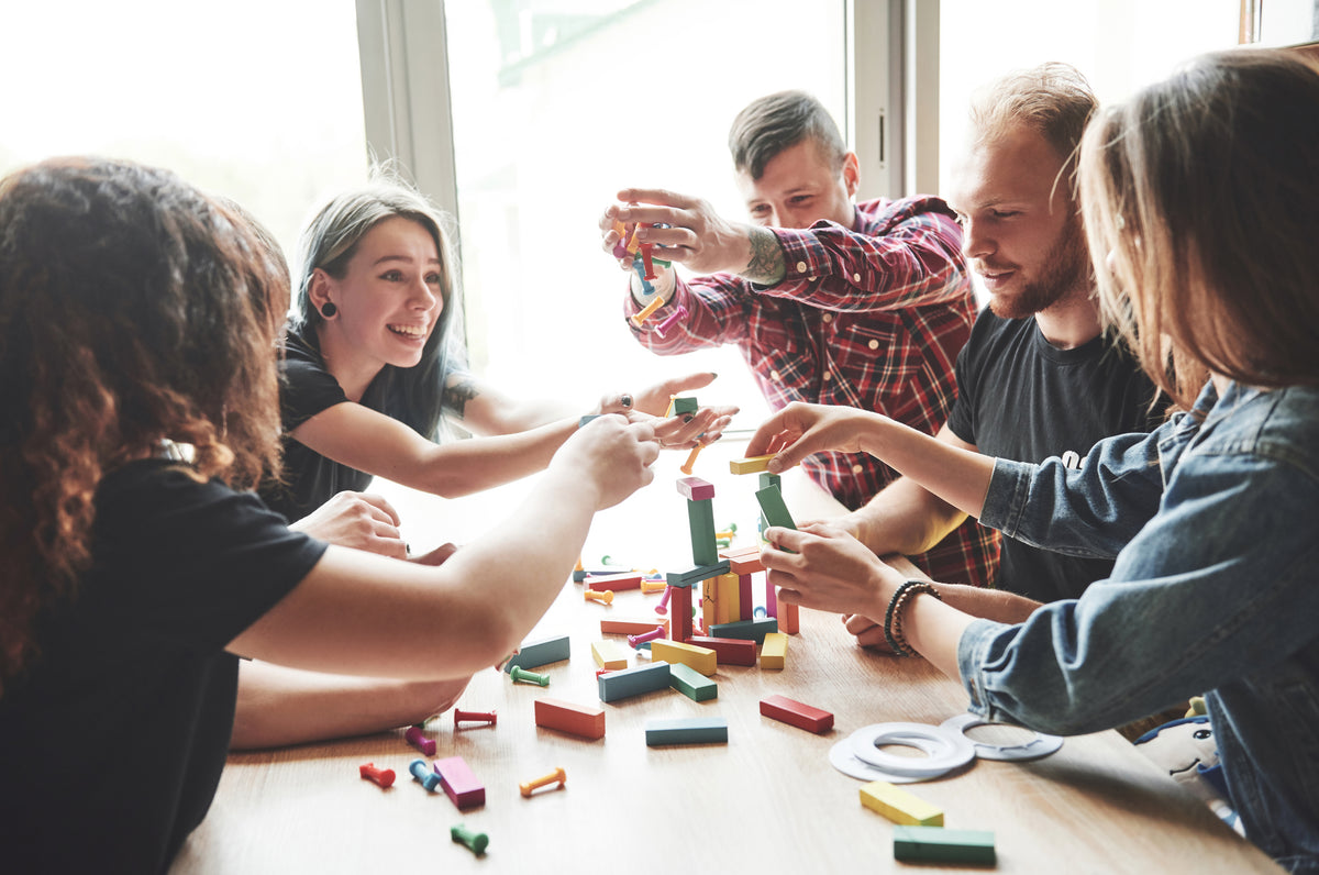Group creative friends sitting wooden table people were having fun while playing board game