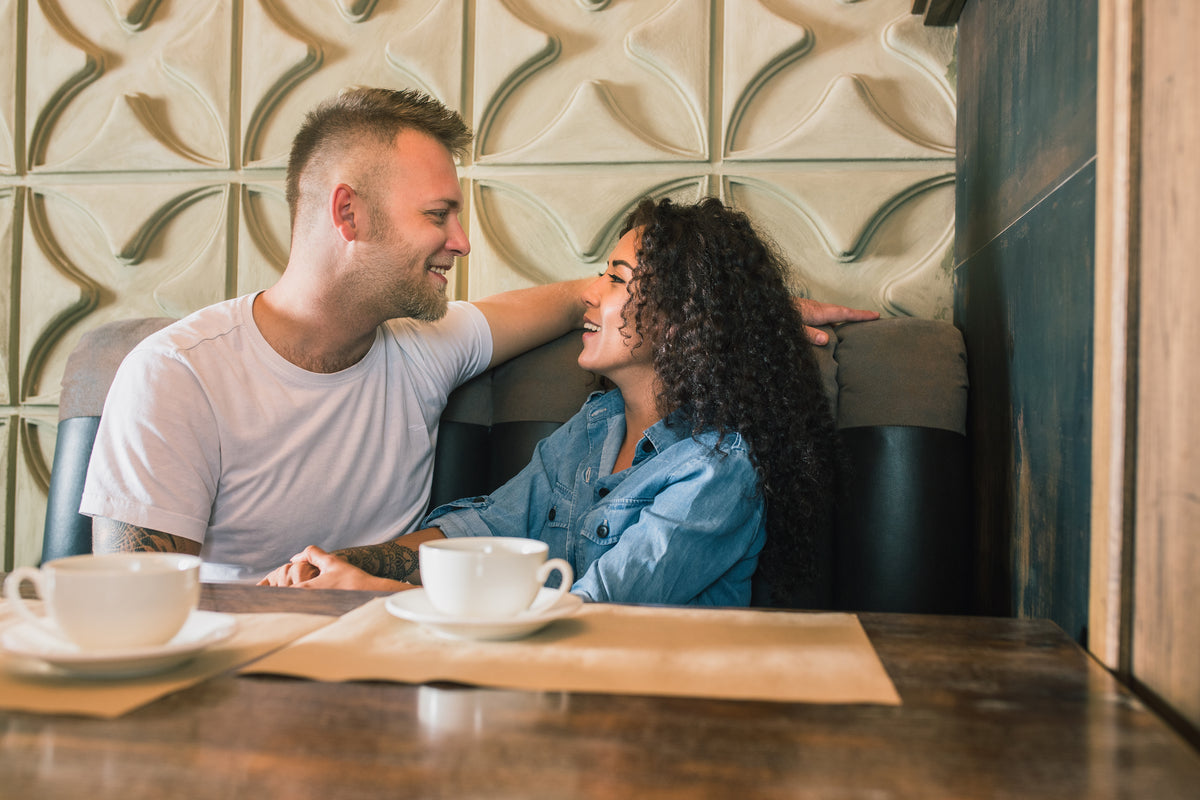 Happy young couple is drinking coffee smiling while sitting cafe