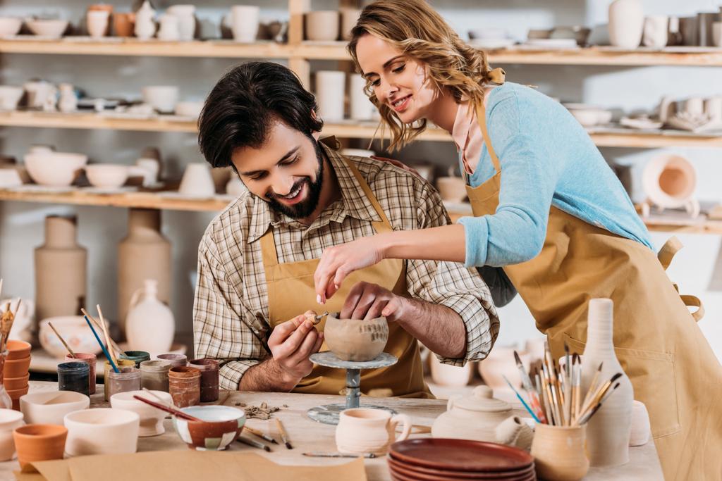 Stock couple potters making ceramic dishware together workshop