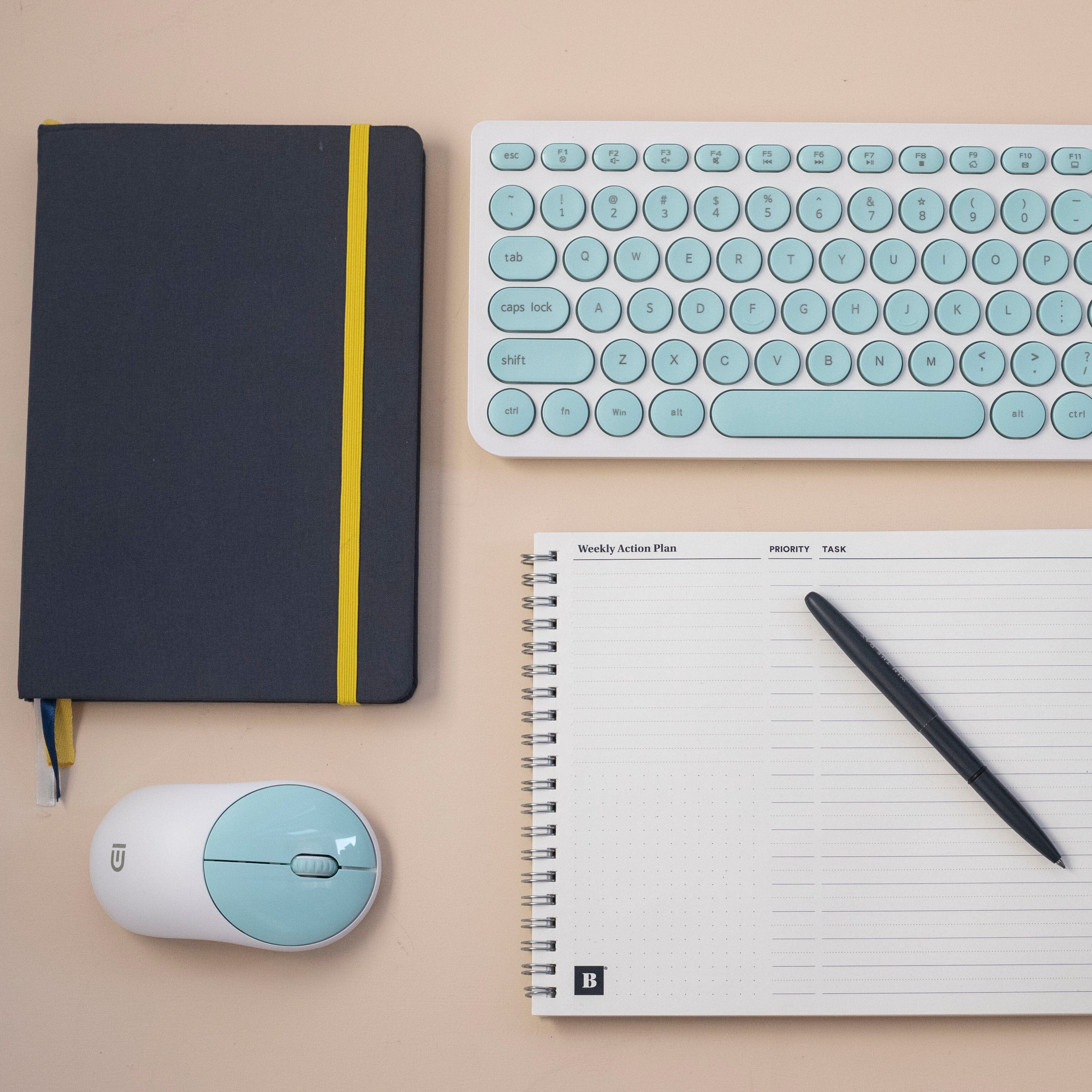 Weekly Action Pad blank with win the day pen, Self Journal, keyboard, and mouse on desk